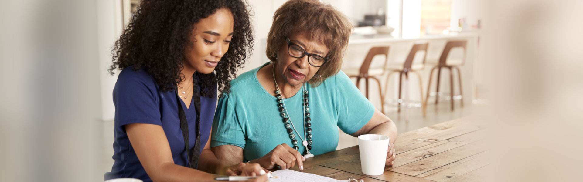 a close-up shot of two women sitting in a kitchen or dining area